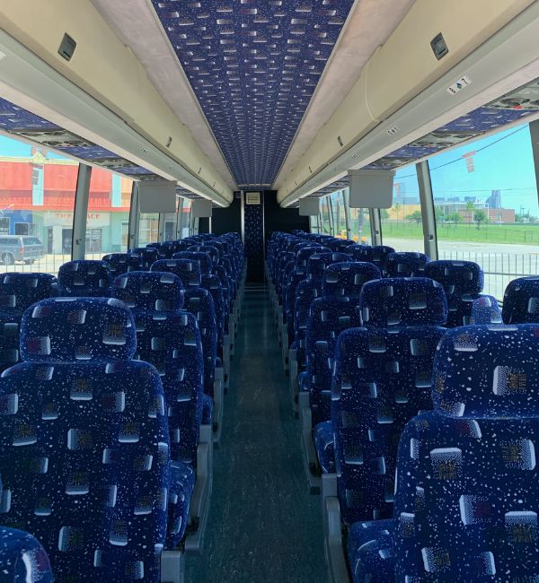 interior of a charter bus rental showcasing rows of plush seating, panoramic windows, and onboard tv screens