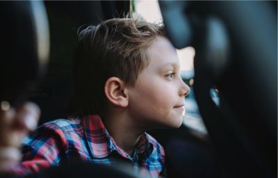 A young boy smiles thoughtfully as he looks out of a bus window.